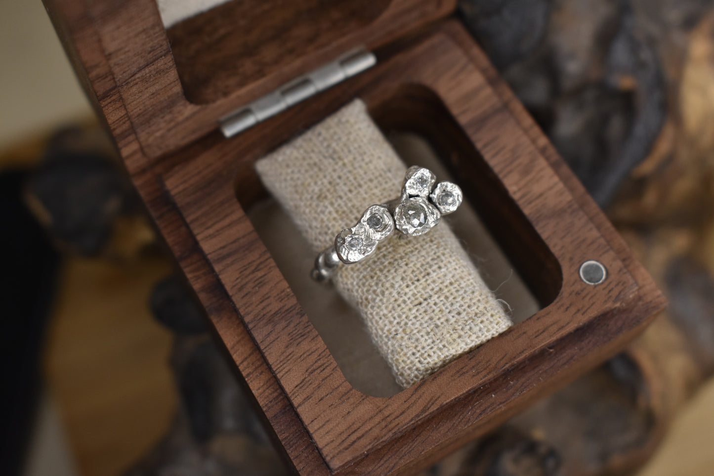 Silver diamond ring in a wooden ring box.