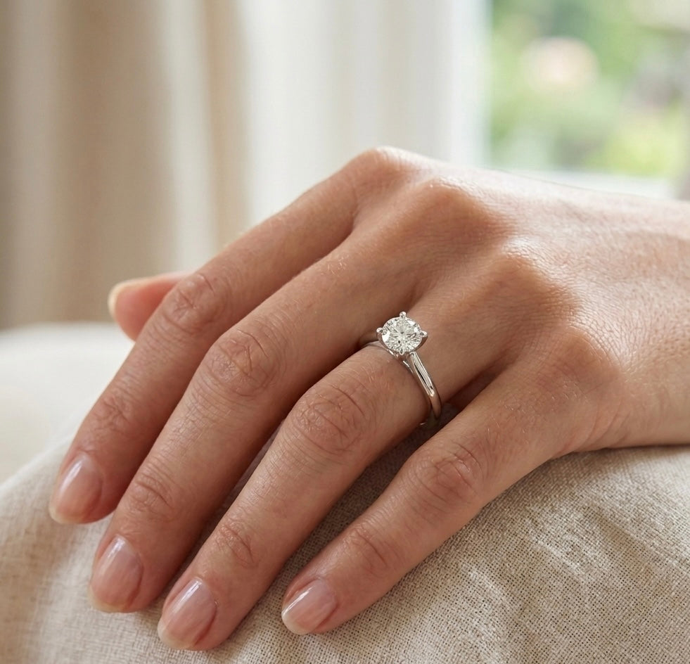 Hand wearing a diamond ring on a neutral background