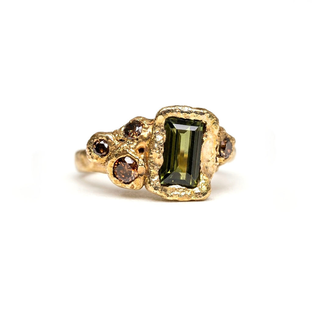 14k yow gold. Green 1 carat sapphire and cognac diamond, organic ring. Made to resemble the eroded cliffs of Swanage. On a white background. 