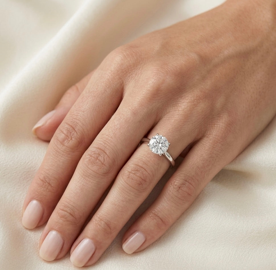Hand wearing a 0.75ct diamond ring on a light fabric background
