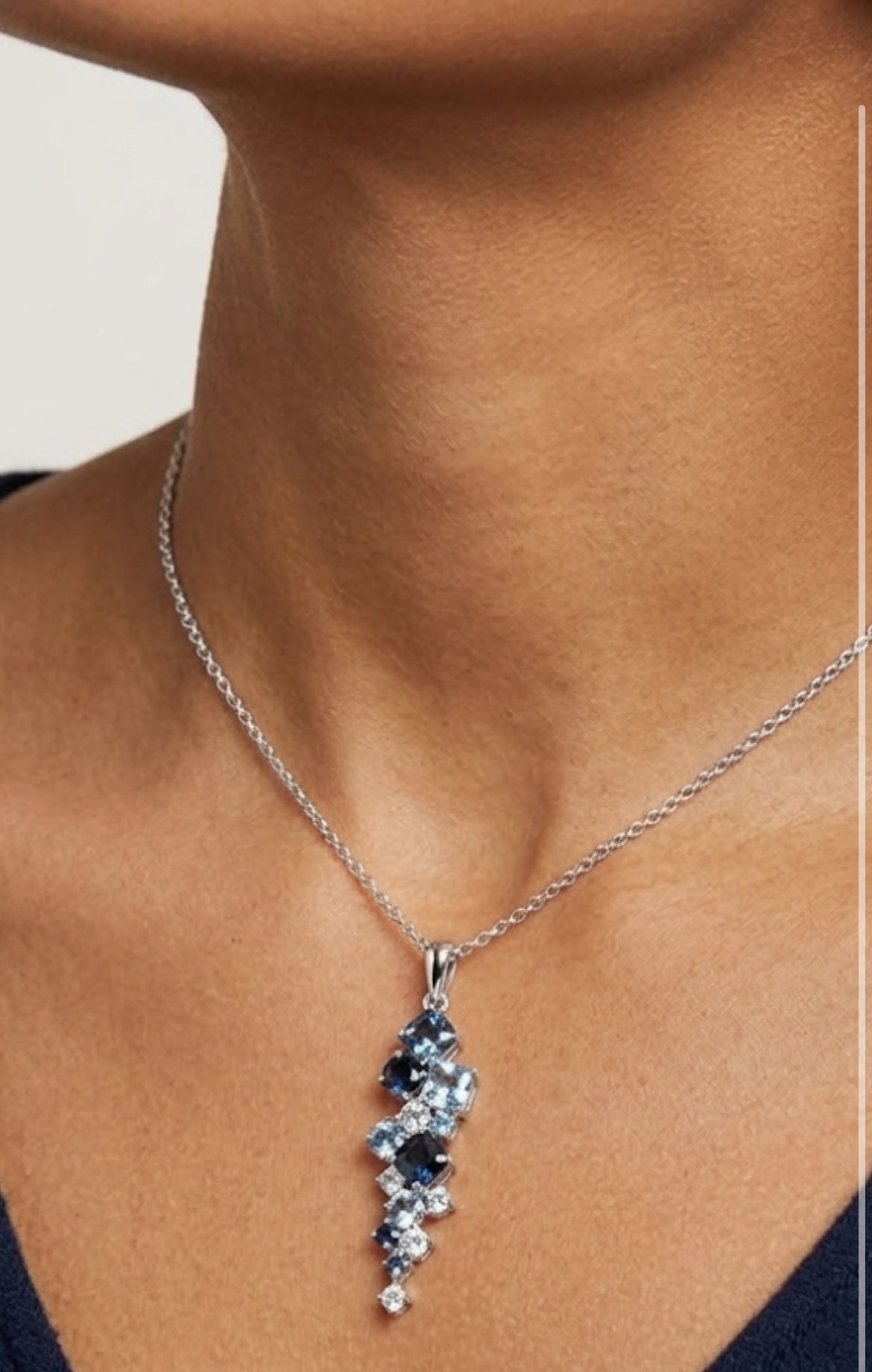 Necklace with a pendant featuring blue stones worn by a person. Jewellery made in the Lake District. 