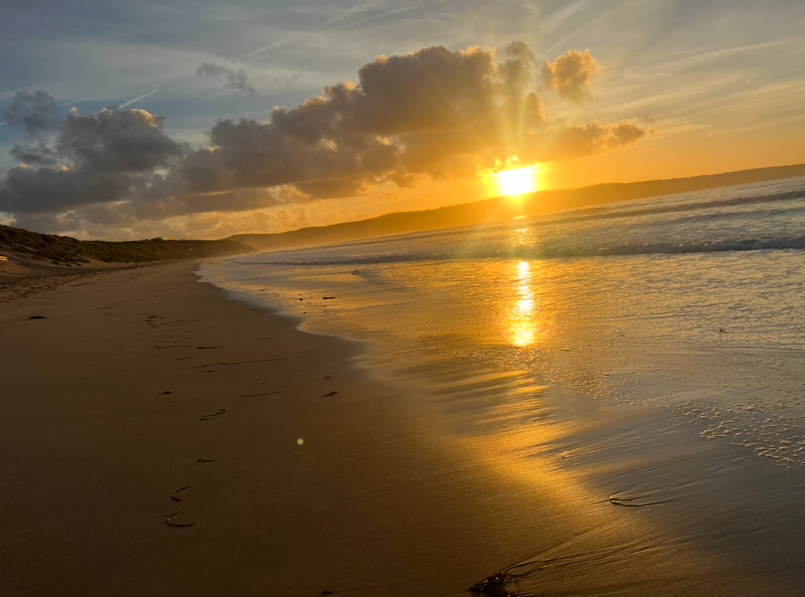 Sunset over a beach with waves and clouds. Wedding rings made on a Cornish beach. 