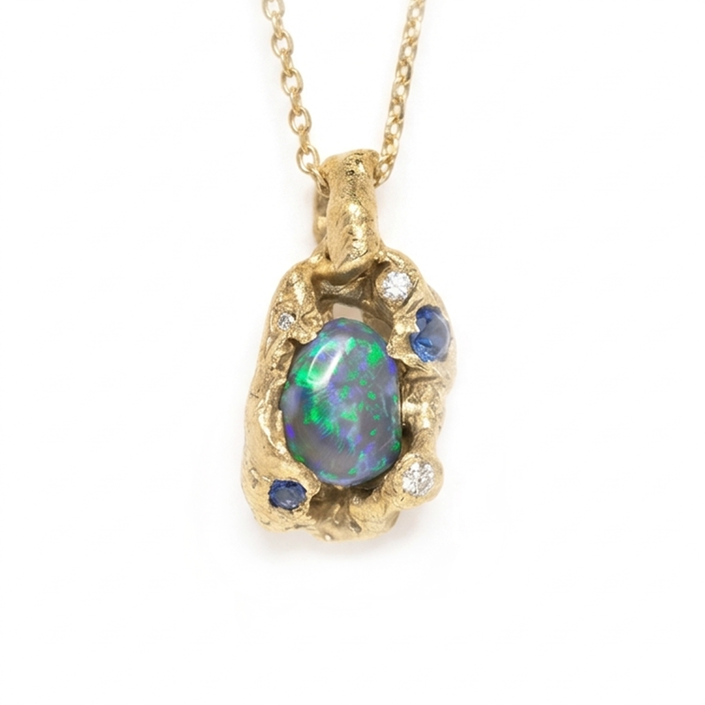 Gold pendant with an opal and sapphire stone on a white background. Jewellery made in Cornwall. Shem Hake Jewellery. 