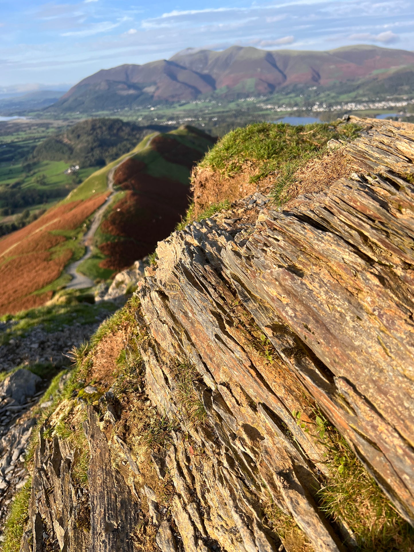 Aerial view of a rugged cliff face with greenery. Gold pendant made in the Lake District. Cat Bells. 