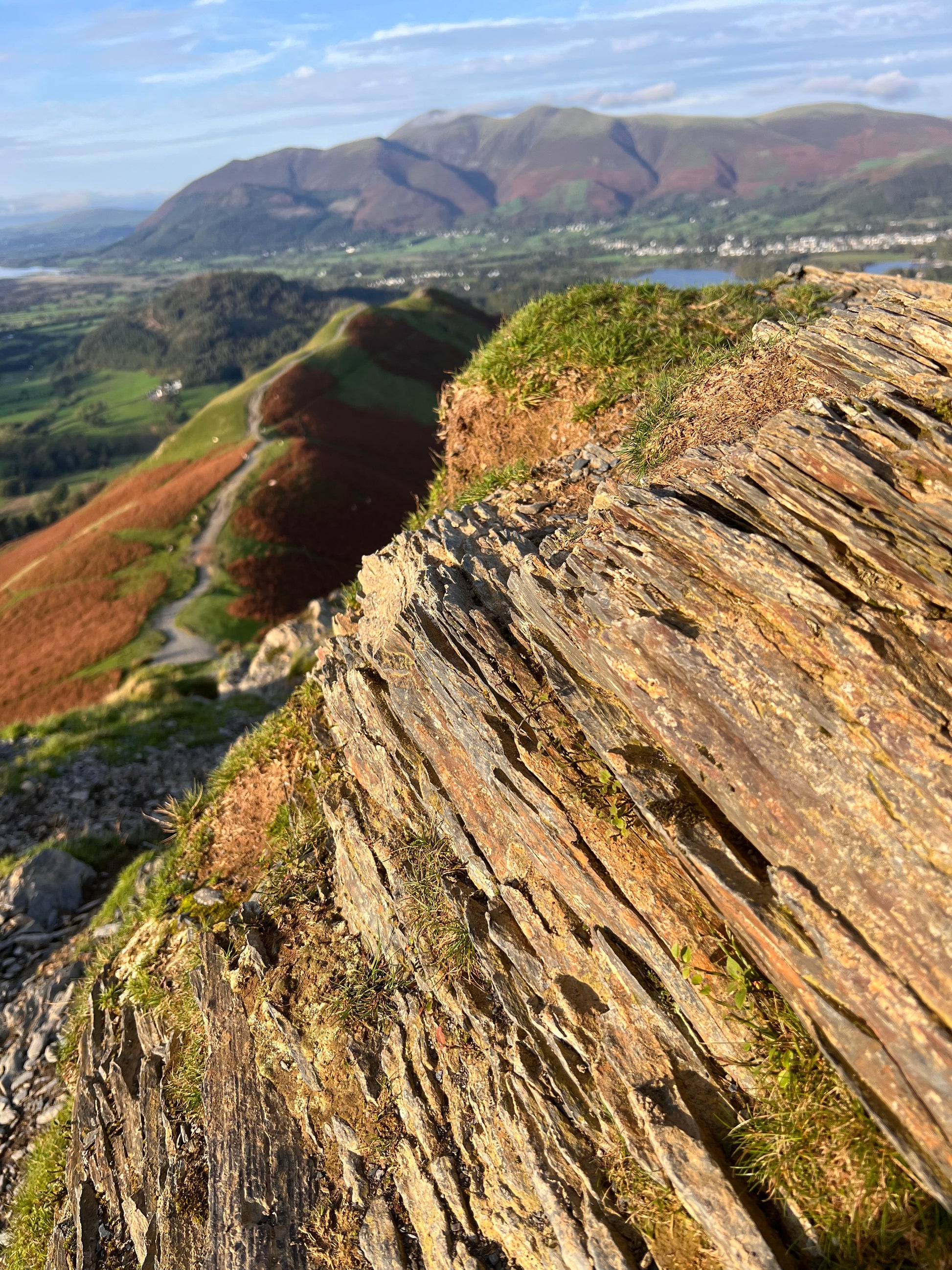 Aerial view of a rugged cliff face with greenery. Gold pendant made in the Lake District. Cat Bells. 